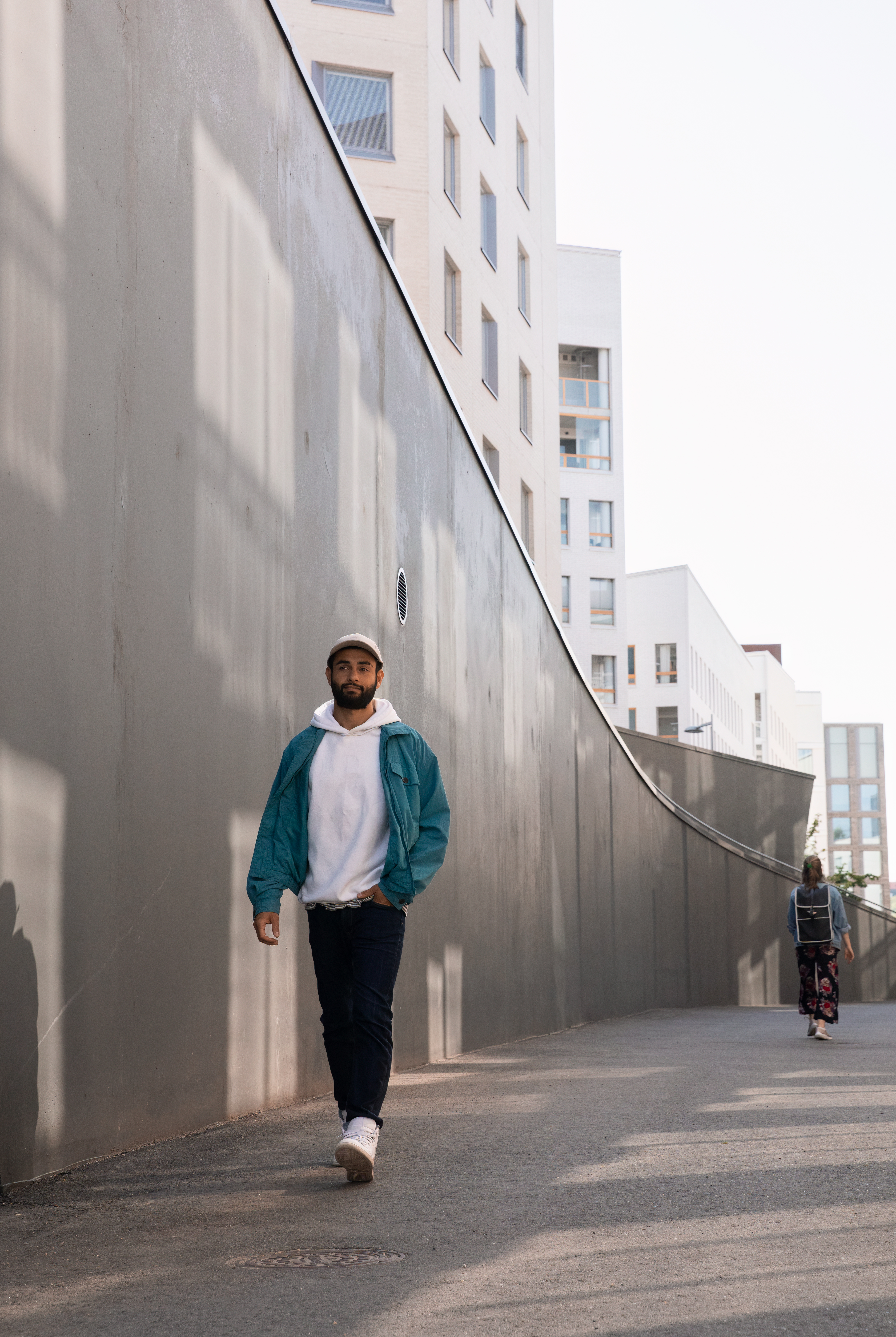 Man walking beside a concrete wall