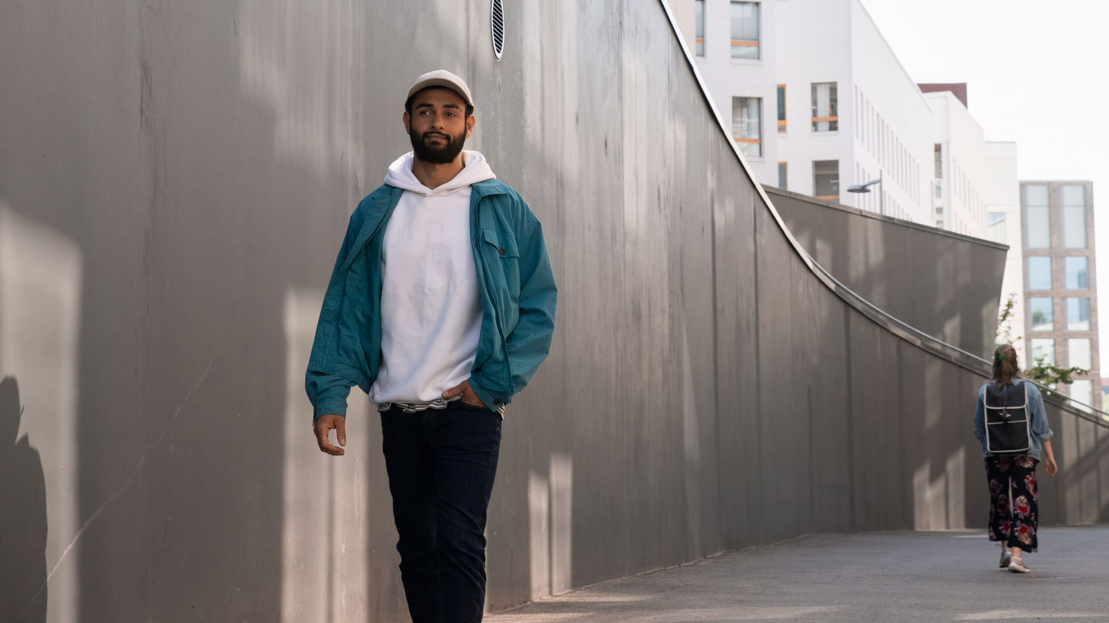 Man walking beside a concrete wall